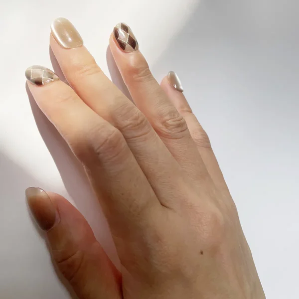 Close-up of coffee brown and nude cat eye press-on nails with argyle pattern