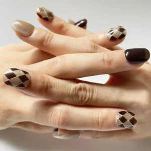 Hand wearing trendy short brown and nude cat eye fake nails with argyle pattern