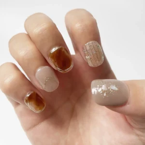 Amber tortoiseshell and nude press-on nails with gold detailing and pearl shimmer on right hand
