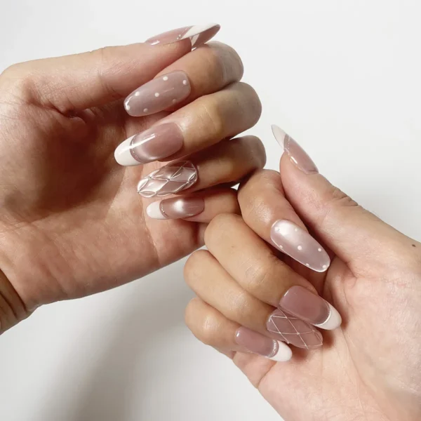 Close-up of long oval soft pink cat eye cat eye fake nails with quilted and polka dot accents