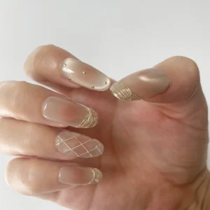 Rose gold-pink cat eye press-on nails with gold French tips on right hand