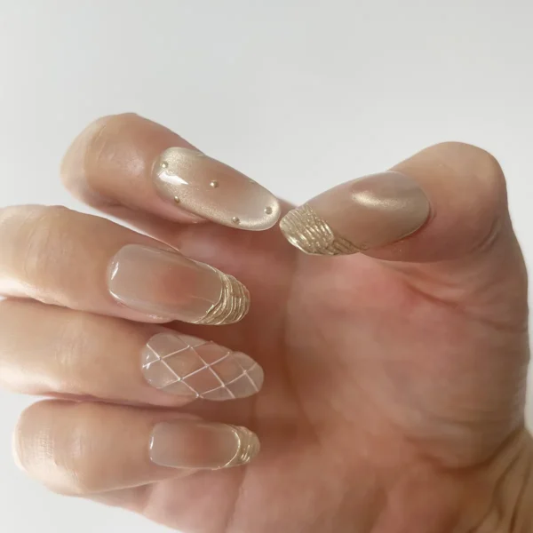 Rose gold-pink cat eye press-on nails with gold French tips on right hand