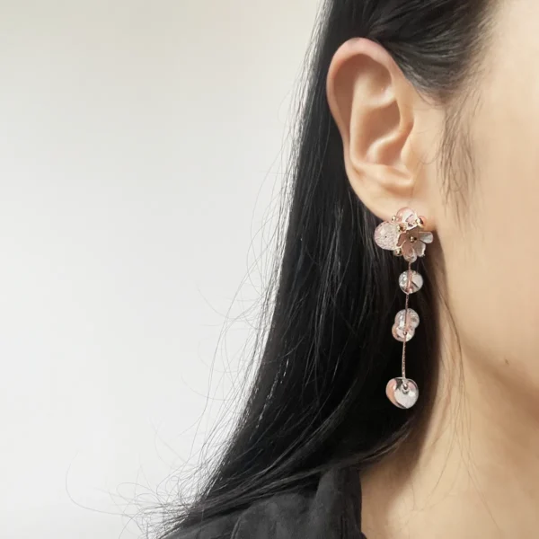Model wearing detachable tassel earrings with silver flower studs and resin beads