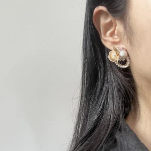 Model wearing brass floral earrings with cotton pearls and Austrian crystals