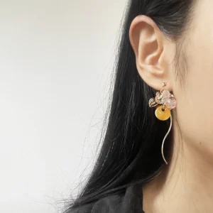 Model wearing whimsical dangle earrings with resin, pumpkin, and mushroom beads